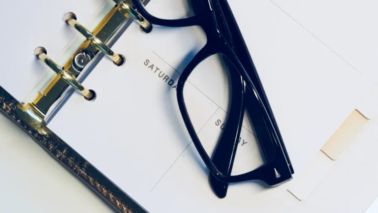 Open ring-bound weekly planner with glasses resting on it, used to map out a content marketing plan