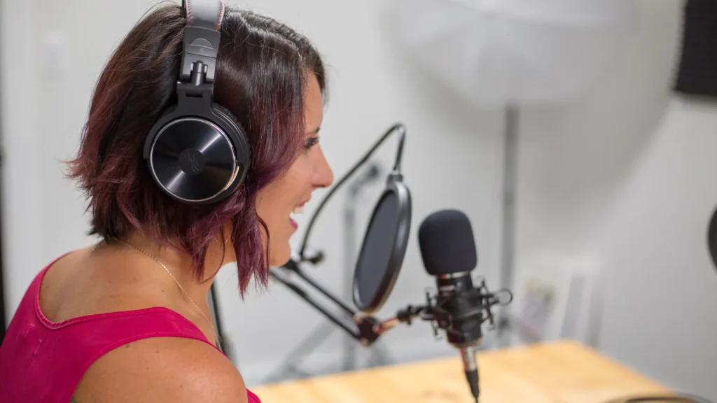 Woman wearing headphones speaking into a studio microphone while recording an interview