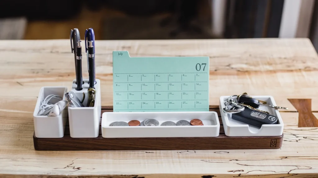 Desk organiser with a monthly calendar card and pens on a wooden desk, used for planning an SEO timeline